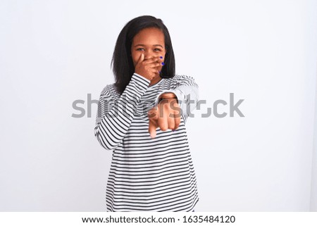 Beautiful young african american woman wearing winter sweater over isolated background laughing at you, pointing finger to the camera with hand over mouth, shame expression
