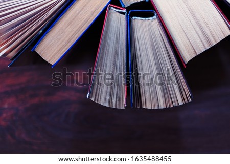Old and well used hardback books or text books in a book shop or library. Many Books Piles. Hardback books on wooden table top view. Back to school background with copy space