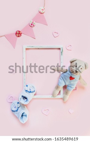 Greeting card for a newborn baby. Set of children's accessories on a pastel pink background. Template for text in a frame.