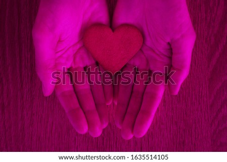 Toned in magenta pink color picture of Woman's hands holding a heart. The symbols of love. Baking lovers on Valentine's Day.
