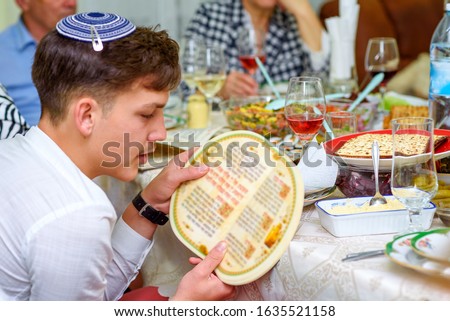 Jewish family celebrate Passover Seder reading the Haggadah. Young jewish boy with kippah reads the Passover Haggadah. Royalty-Free Stock Photo #1635521158