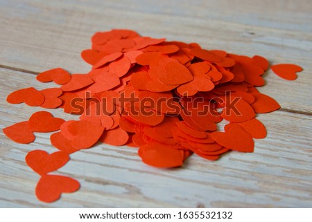 A pile of red little hearts to express love against a wooden background