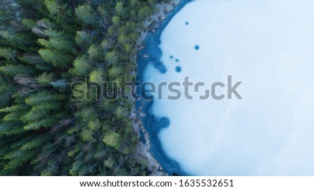 Aerial view of a beautiful frozen lake and forests in winter. Photo of the northern nature of Finland with a drone.