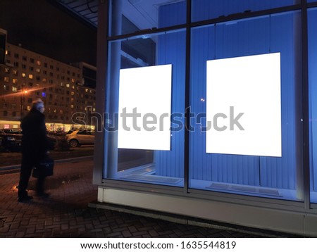 advertising poster in the window on the display window glowing. on a blue background in the late evening