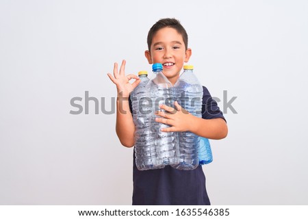 Beautiful kid boy recycling plastic bottles standing over isolated white background doing ok sign with fingers, excellent symbol