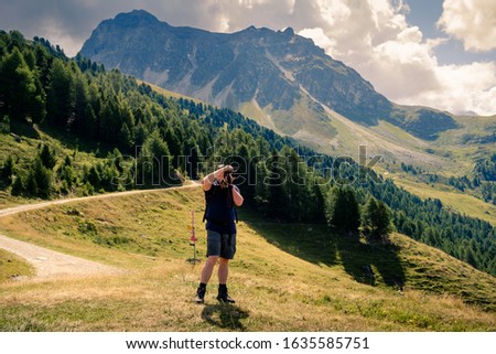 Photographer making a photograph high up in the Pennine Alps near the Swiss village of Saint-Luc in summer. Val d' Anniviers, Valais, Switzerland