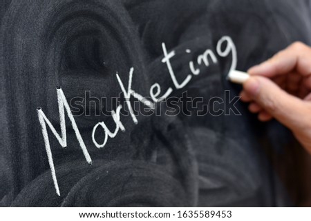 
The word marketing written on the blackboard with a chalk, out of focus