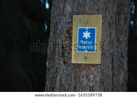 sign with the inscription "reserve" nailed to a tree in the forest