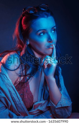 Fashionable Artistic Portrait Of A Beautiful Female Model In Bright Lights. resentful or brooding facial expression