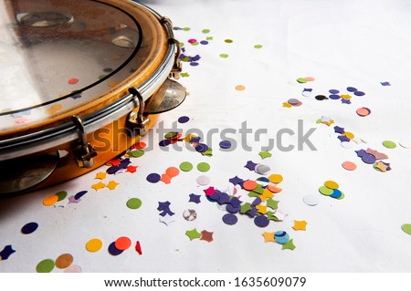 Pandeiro, traditional samba instrument, used in the Brazilian carnival. White background, paper confetti. Seen from above. Space for text. Horizontal. Royalty-Free Stock Photo #1635609079