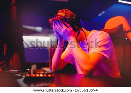 Gamer young man is defeated in online video game, anger and facepalm, screaming and emotion, neon color. Internet addiction concept.