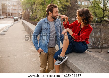 attractive happy smiling man and woman in hipster casual outfit traveling together in Europe, stylish couple in love flirting sitting in street on romantic trip, sunny autumn city, having fun romance Royalty-Free Stock Photo #1635621157