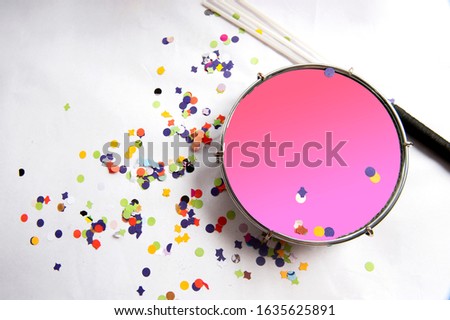 Traditional samba instrument, tambourine is used in the Brazilian carnival. White background, paper confetti. Seen from above. Space for text. Horizontal. Royalty-Free Stock Photo #1635625891