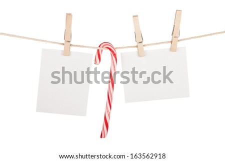 Blank photos and candy cane hanging on clothesline. Isolated on white background