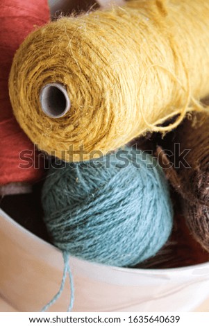 Various rolls of colorful twine and yarn for crafting in a basket.