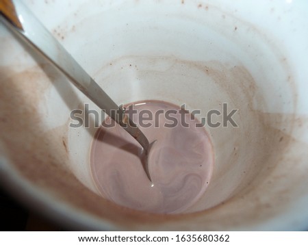 there is a spoon in a cup with cocoa residue