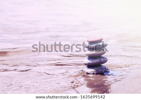 Wet pebbles stacked on water edge. Meditation, harmony, balance  and zen symbols as background in pastel colors