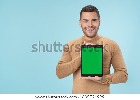 Smiling caucasian man showing digital tablet isolated on blue background