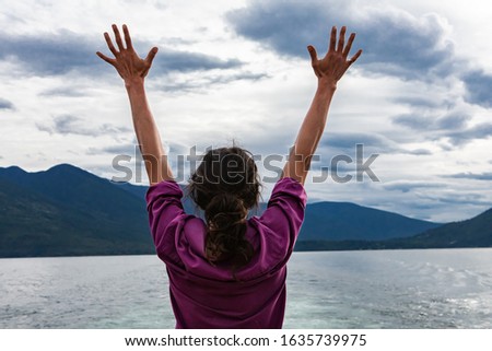 Close up from behind of a man on the deck of a passenger ferryboat. Arms raised and hands with fingers spread open. Freedom concept.