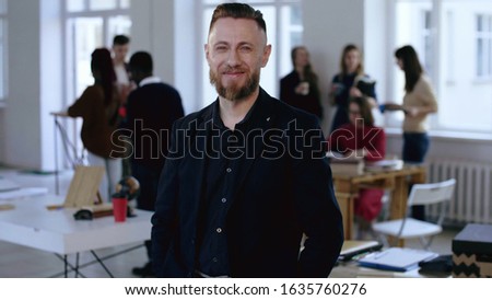Medium portrait of confident successful middle aged European male executive CEO manager smiling at camera at office.