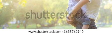 Beautiful young asian mother carrying little boy in the park, asia woman happy having son and hug kid, mom love and embracing child together in summer, mother day and family concept, banner website.