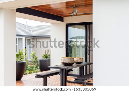 A contemporary style Patio with a stylish black snack counter and benches and two black high flower pots.