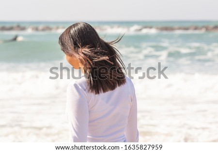 A teenage girl with her hair blowing in the wind against the sea