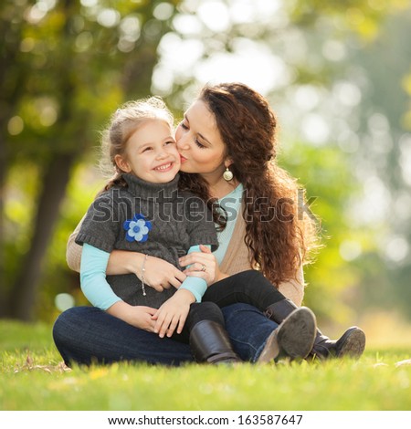 Mother kissing her daughter in the park