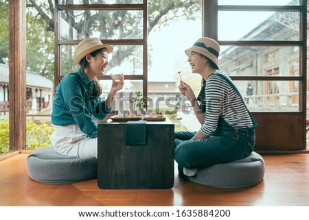 side view of two asian girls having fun laughing during afternoon tea time in local tea shop. Japanese style house Tokyo Japan. group of cheerful female friends enjoy local snack eating indoor Royalty-Free Stock Photo #1635884200
