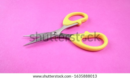 Top view of Yellow scissors isolated on pink background.Scissors use for cutting paper and thin materials.