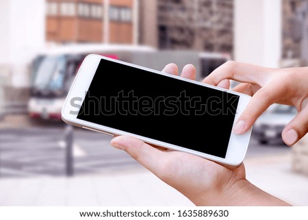 woman hand hold and touch screen smart phone or cellphone on city traffic in morning background.
