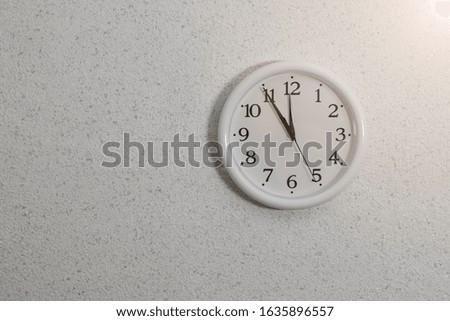 Analog clock with hands on the wall with textured plaster. Device for determining the time.