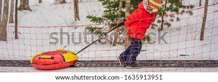 Boy with tubing rises on a travelator to the mountain. Child having fun on snow tube. Boy is riding a tubing. Winter fun for children BANNER, LONG FORMAT