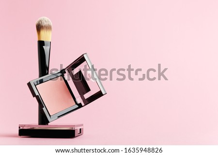 Composition with makeup items on a white background. Black brush, makeup tool, packing of rouge and powder levitate on a pastel backdrop. Set of beauty products for face, lips and eyes with copy space Royalty-Free Stock Photo #1635948826