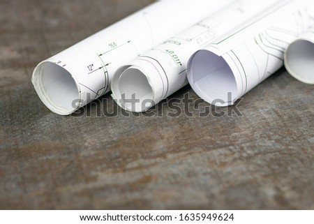 Wooden background. On it are blueprints or a plan of the future home or knowledge. They are rolled up