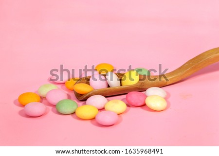 colorful candy on wooden spoon isolated on pink background