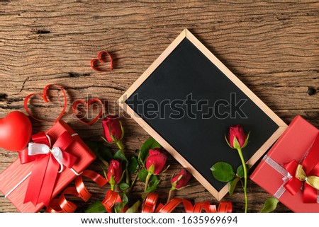Blank blackboard with red roses and heart ribbon on old wood background, Valentine's day background concept