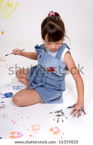 A girl makes handprints on the background paper.