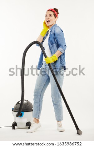 Pretty woman in work-wear uses a big wacuum cleaner.