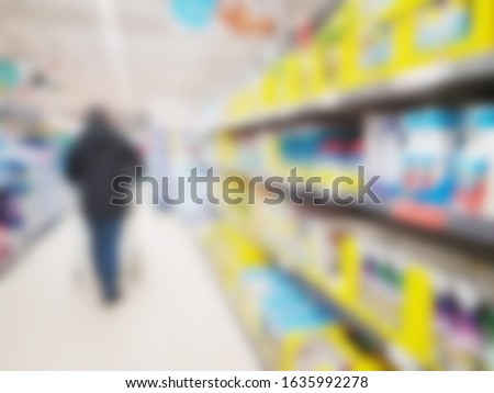 Abstract blurred view of a shopper in a supermarket shop store aisle with products for sale displayed on shelving