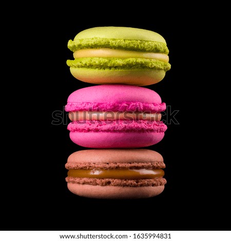 Row of french colorful macaroon or heap of them on wooden table isolated on black background with clipping path