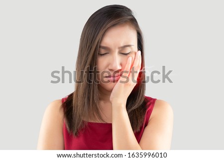 Have a hypersensitive teeth, Suffering from toothache. Beautiful young woman suffering from toothache while standing against grey background Royalty-Free Stock Photo #1635996010