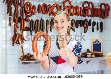Woman selling sausages giving the thumbs up sign recommending them for taste and quality