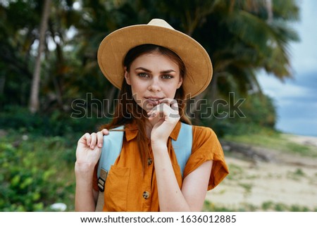 A woman with a backpack on her back and looking at the camera on the nature