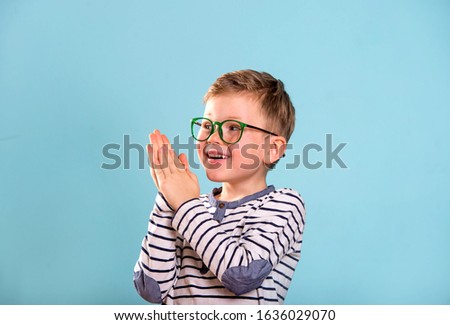 Happy exciting child boy giving applaud.  School kid clapping hands isolated on blue background. 