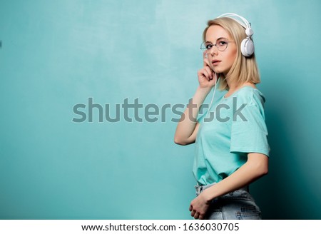 Style blonde woman in glasses with headphones on blue background