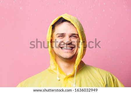happy guy in a yellow raincoat on a pink background