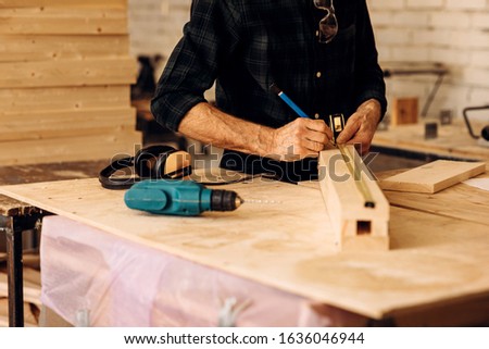 Cropped shot of caucasian mature carpenter measuring a wooden plank in workshop