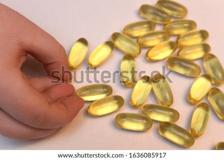 Vitaminen Omega 3 fish oil in capsules in hand on beige background.