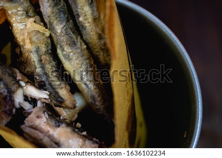 Fried anchovies in foil on brown background